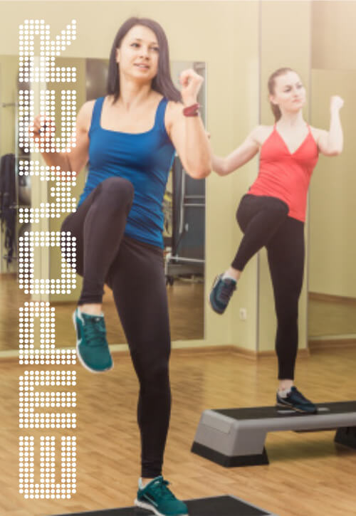 2 women using aerobic steppers